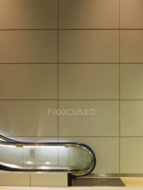 Panelled wall behind escalator in airport. — Stock Photo