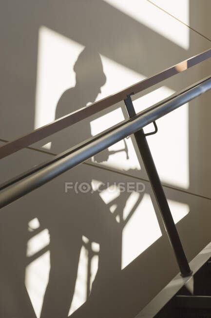 Тень строителя, поднимающегося по лестнице по стене с перилами. — стоковое фото