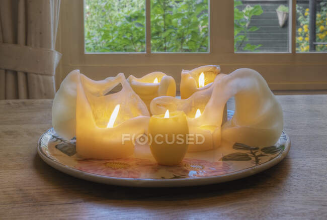 Розтоплені воскові свічки на тарілці на обідньому столі . — стокове фото