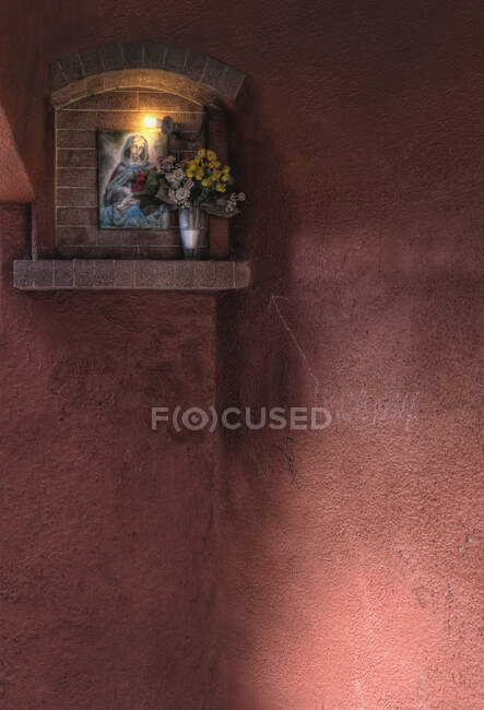 Shrine to the Virgin Mary on wall lit up at night. — Stock Photo