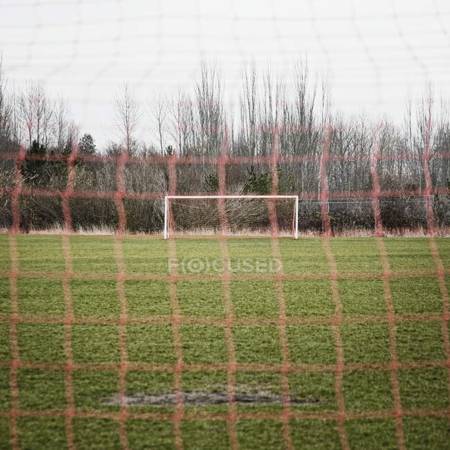 Campo de futebol visto através da rede de golos de futebol — Fotografia de Stock