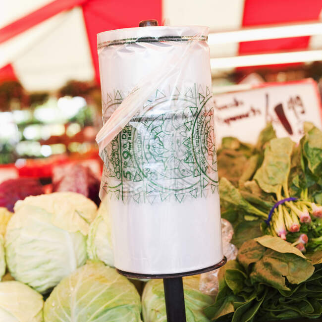 Rotolo di sacchetti di plastica su bancarella vegetale nel mercato. — Foto stock