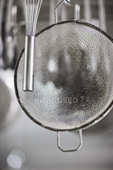 Whisk and sieve hanging in commercial kitchen. — Stock Photo