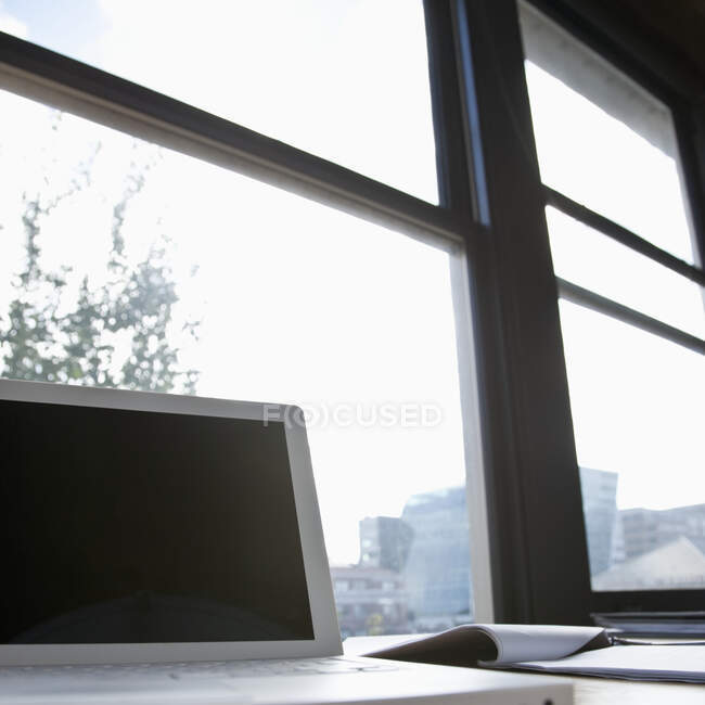Laptop in front of window on urban skyline. — Stock Photo