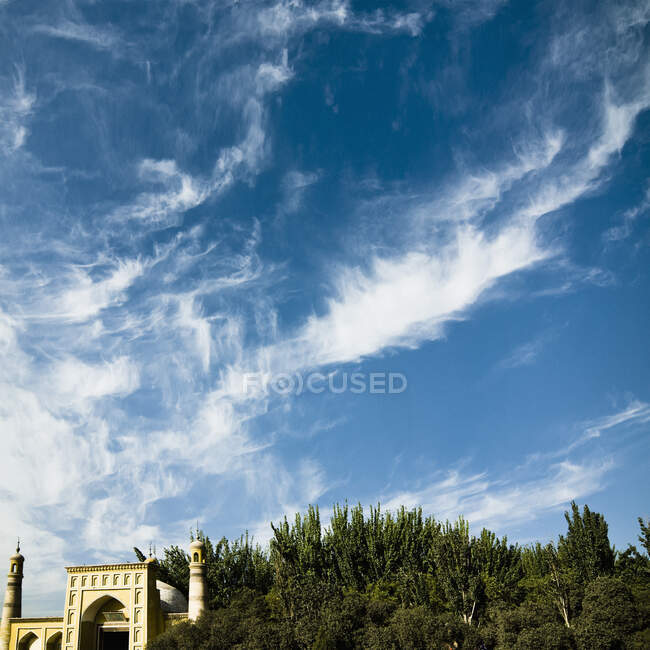 Mosque entrance and minaret with trees and sky. — Stock Photo