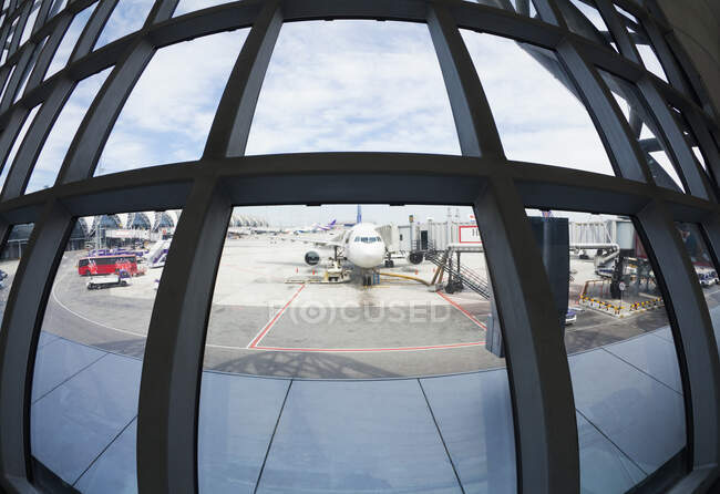 Lente de olho de peixe vista de aviões estacionados no asfalto do aeroporto a partir da janela do terminal. — Fotografia de Stock