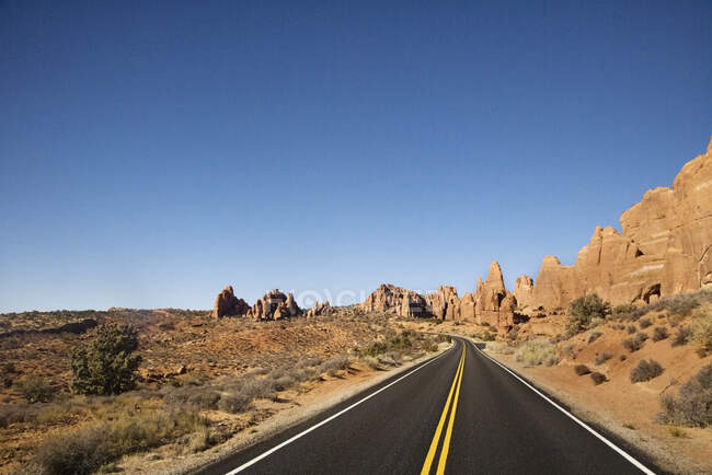 Road reaching into the distance, horizon with jagged rocks — Stock Photo