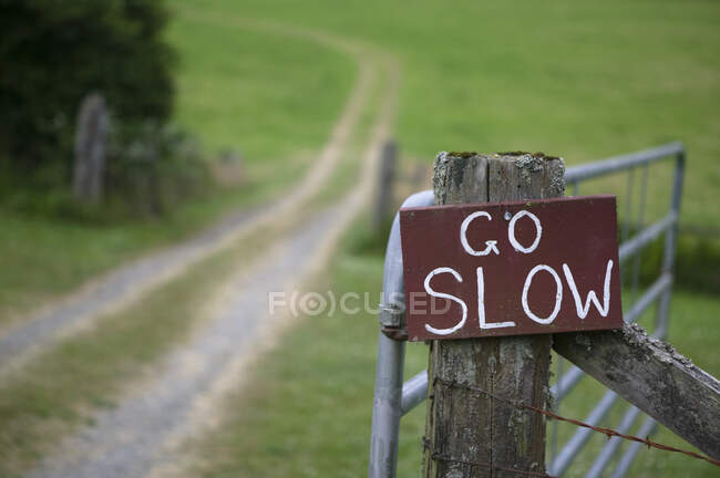 Go slow sign on wooden countryside gate. — Stock Photo