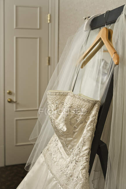 Vestido de noiva e véu pendurado no rack no quarto do hotel. — Fotografia de Stock