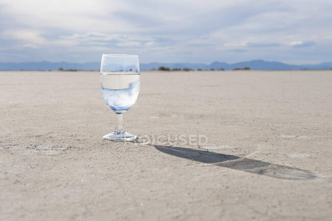 Glass of drinking water on salt flat. — Stock Photo