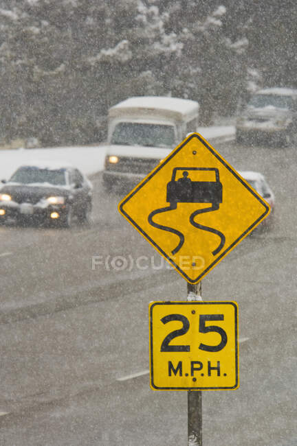 Conducción de tráfico en carretera nevada con advertencia de peligro de derrape. - foto de stock
