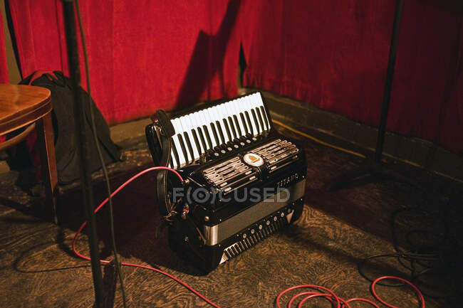 Accordion plugged in on floor of performance venue — Stock Photo