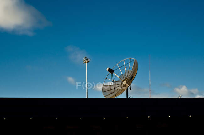 Una antena parabólica y torre contra el cielo azul - foto de stock