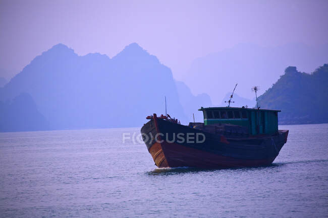 Containerschiff auf dem Wasser mit Bergen dahinter. — Stockfoto