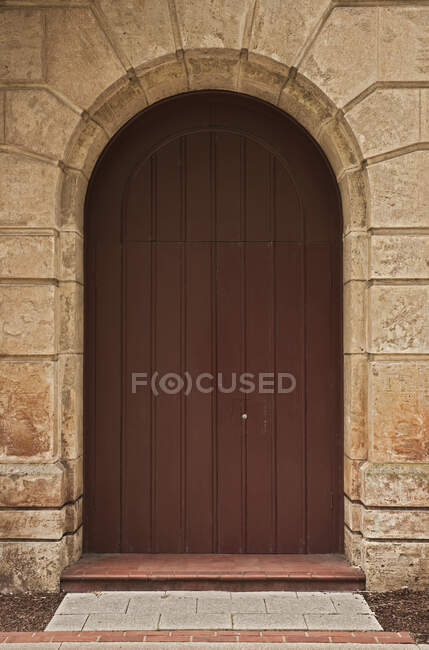 Puerta de madera en arco de piedra. - foto de stock
