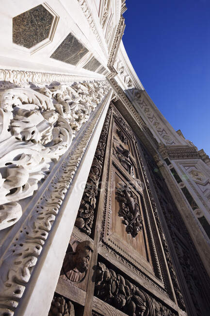 Low angle view of ornate carved wooden doorway and stone building facade. — Stock Photo