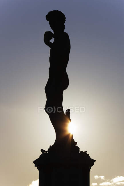Silueta de estatua clásica con puesta de sol detrás. - foto de stock