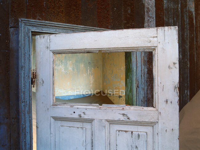 Porta de madeira aberta em um edifício enterrado na areia. — Fotografia de Stock