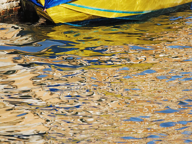Amarillo amarre barco con reflejos en el agua. - foto de stock
