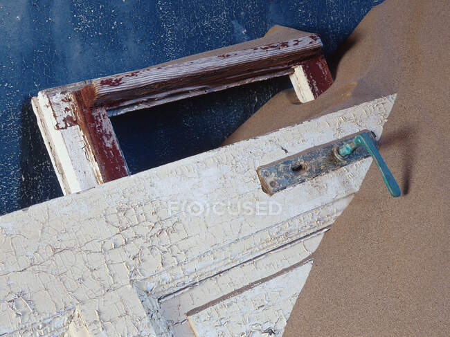 Vista de la puerta de madera maltratada enterrada en arena. - foto de stock