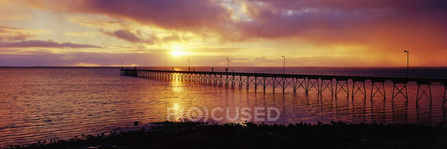 Pier im Meer mit Sonnenuntergang am Horizont des Ozeans. — Stockfoto