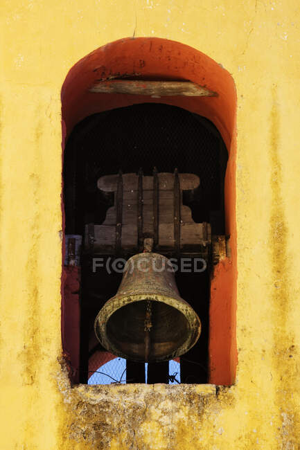 Bell tolling in a yellow painted arch. — Stock Photo