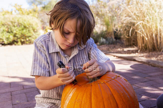 Молодий хлопчик різьблення гарбуз на патіо . — стокове фото