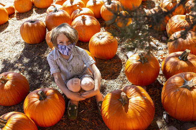 Young boy in face mask in pumpkin patch. — Stock Photo