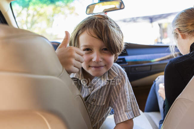 Jeune garçon regardant la caméra dans la voiture garée. — Photo de stock