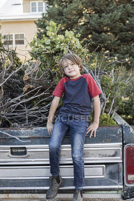 Молодий хлопець, сидячи на старому пікапі, повний щіткового дерева — стокове фото