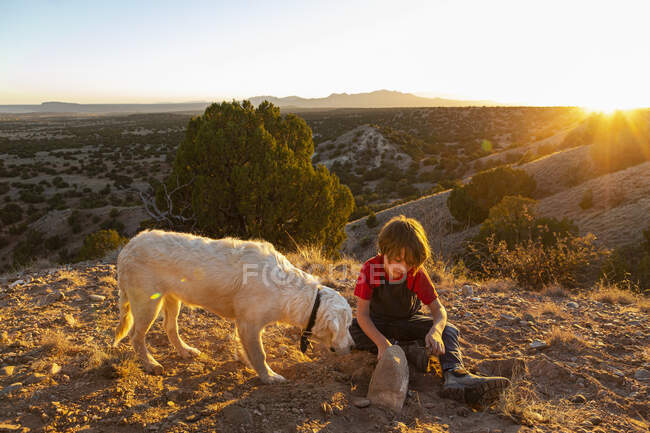 Kleiner Junge im Galisteo Basin bei Sonnenuntergang mit seinem English Cream Golden Retreiver — Stockfoto