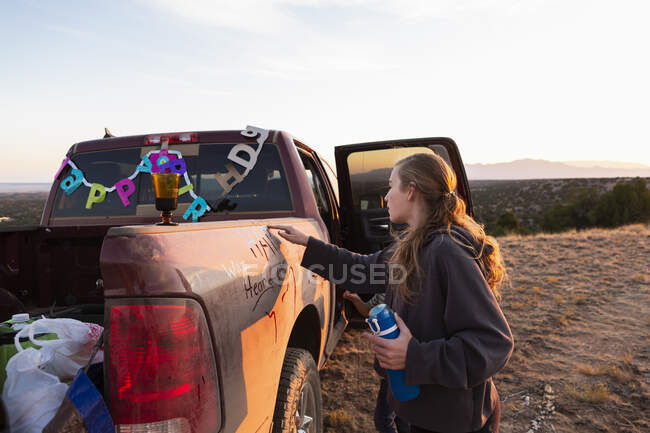Teenage girl writing on dirty pickup truck — Stock Photo