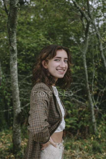 Retrato de una niña feliz de diecisiete años parada en un frondoso bosque en otoño, Discovery Park, Seattle, Washington - foto de stock