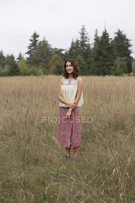 Porträt eines glücklichen siebzehnjährigen Mädchens, das auf einem Feld mit hohen Gräsern steht — Stockfoto