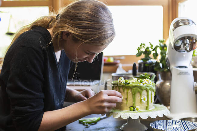 Adolescente na cozinha aplicando a cereja ao bolo — Fotografia de Stock