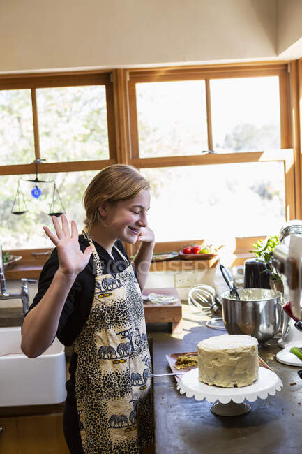 Teenager Mädchen in der Küche Anwendung Sahnehäubchen auf Kuchen — Stockfoto