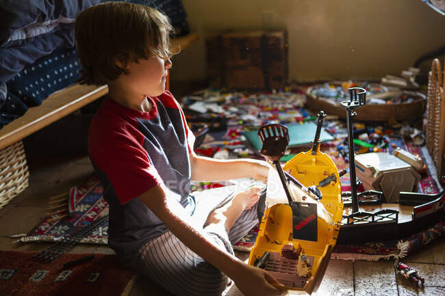 Vue grand angle du jeune garçon dans sa chambre jouant avec ses jouets — Photo de stock