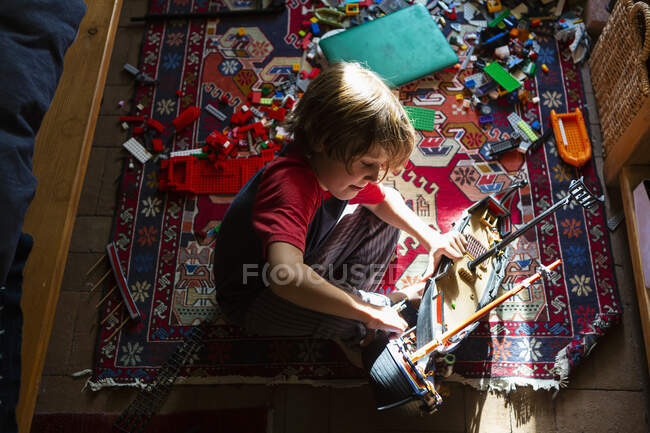 Високий кут зору молодого хлопчика в своїй кімнаті граються з його іграшками — стокове фото