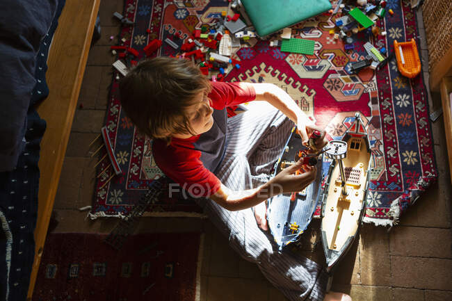 Vue grand angle du jeune garçon dans sa chambre jouant avec ses jouets — Photo de stock