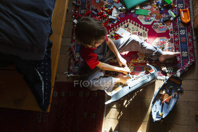 Високий кут зору молодого хлопчика в його кімнаті, граючи зі своїми іграшками — стокове фото