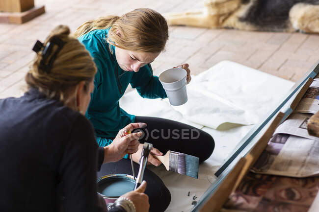 Mère et adolescente peignent des étagères sur une terrasse — Photo de stock