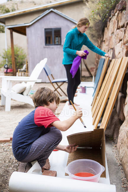 Ragazza adolescente e un ragazzo di sette anni che dipinge scaffali con vernice blu. — Foto stock