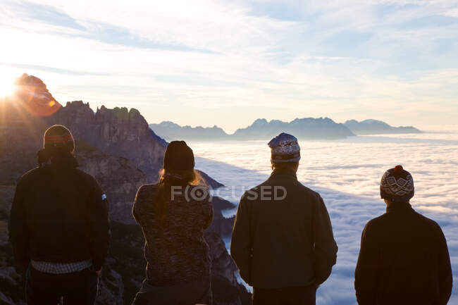 Grupo de jóvenes observando el amanecer sobre las nubes, Trentino-Alto Adigio, Tirol del Sur en el distrito de Bolzano, Alta Pusteria, Hochpustertal, Sexten Dolomites, Italia - foto de stock