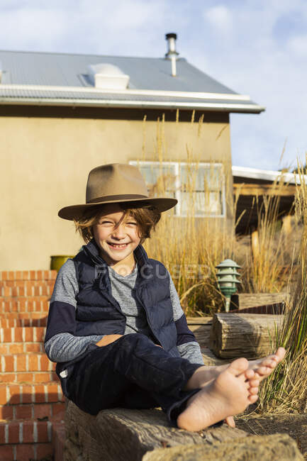 Portrait of young boy wearing fedora hat relaxing on his porch — Stock Photo