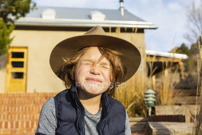 Portrait of young boy wearing fedora hat relaxing on his porch — Stock Photo