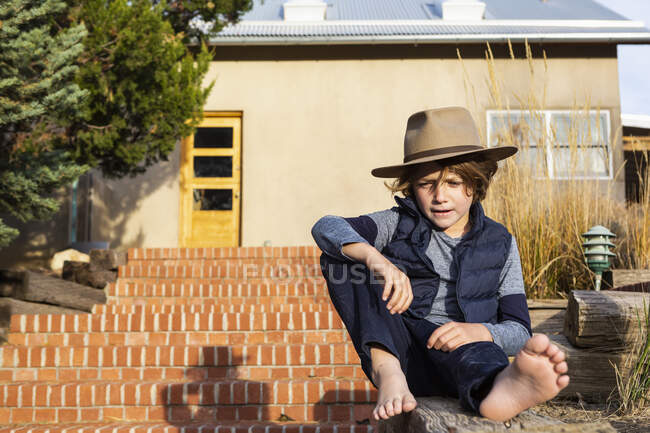 Porträt eines kleinen Jungen mit Fedora-Hut entspannt auf seiner Veranda — Stockfoto