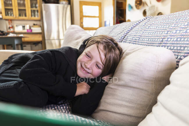 Jovem deitado no sofá olhando para o computador portátil — Fotografia de Stock