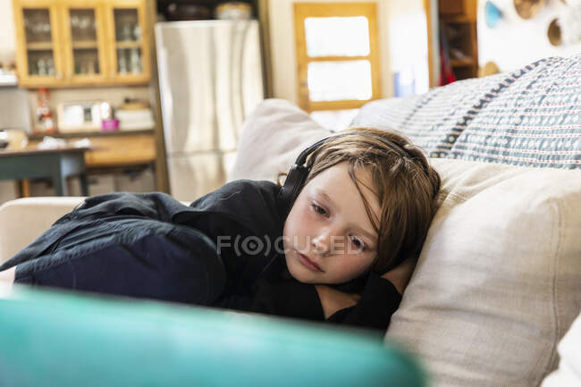 Kleiner Junge liegt auf Sofa und schaut auf Laptop — Stockfoto