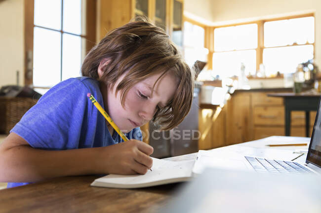 Jovem em casa escrevendo e desenhando em seu bloco de desenho — Fotografia de Stock