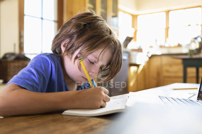 Young boy at home writing and drawing in his drawing pad — Stock Photo